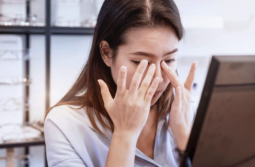 A young professional sits in a well-lit office, rubbing the inner corners of her eyes.