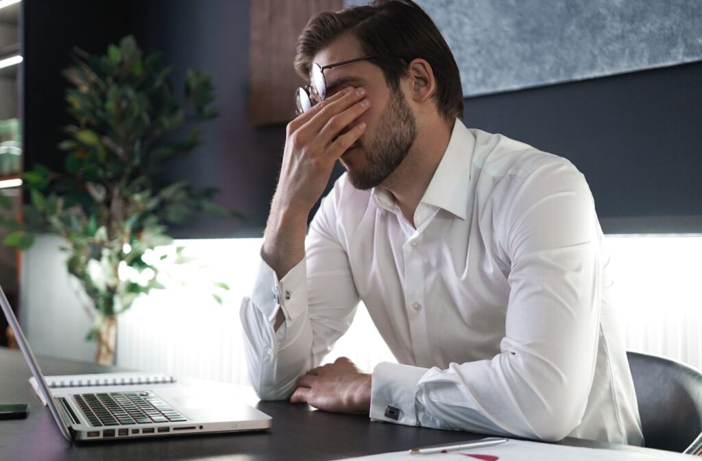 A young man at work rubbing his eyes in discomfort due to dry eyes.