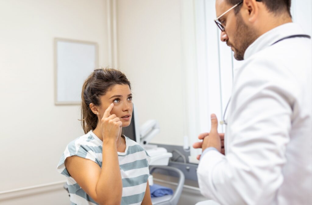 A patient points to their eye while asking their optometrist if eye makeup is suitable to wear with punctal plugs.