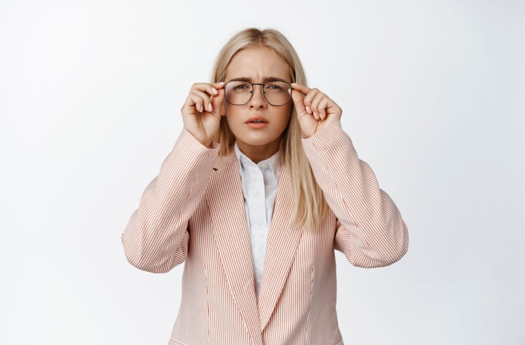 A person struggling to see clearly while wearing prescription glasses.