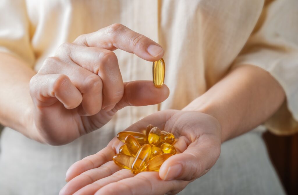 A person holds a hand of omega-3 vitamins for dry eyes and holds one up
