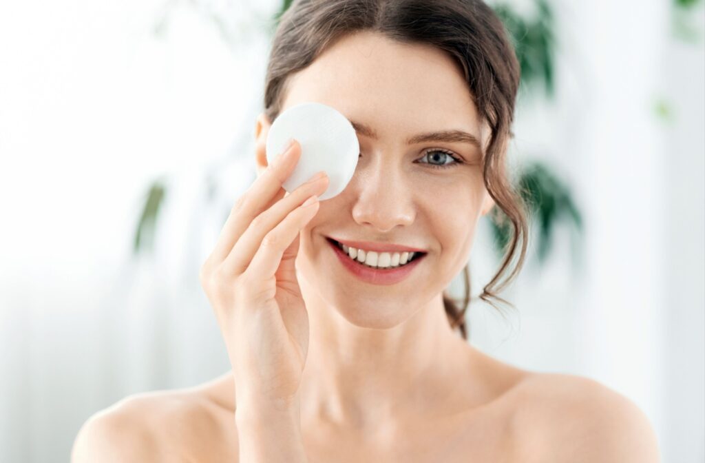 A person holding a cotton pad up to their eye